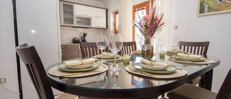 A dining area with a glass table, brown chairs, and a white cabinet in the background.