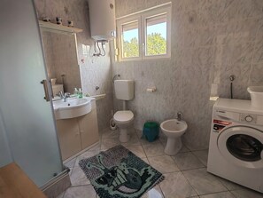 Een badkamer met een wastafel, toilet, bidet en een wasmachine.