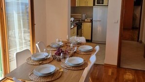 Zona pranzo con tavolo in legno apparecchiato per sei persone, sedie bianche e lampada a sospensione.