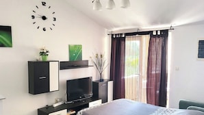 A modern bedroom with a bed, a TV, a desk, and a window with curtains. - Apartments Mirko i Jela (Nin)