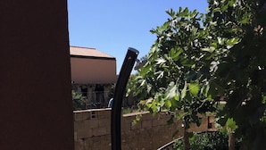 A wooden deck with a metal railing, a stone wall, and a clear blue sky. - Apartments Mirko i Jela (Nin)
