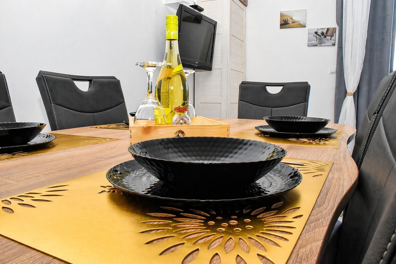 Une table à manger avec des bols noirs, une bouteille de vin et des verres.