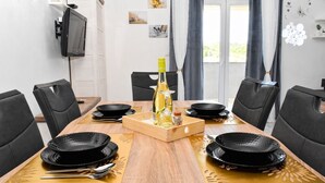 A dining table set with black plates, a bottle of wine, and a wooden tray. - Apartment Belissima Deluxe (Rab)
