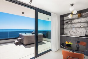 En moderne balkon med jacuzzi, spiseplads med bord og stole, samt et køkken med marmor bordplader.