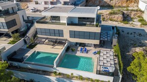 A modern multi-story residential building with a rooftop pool and outdoor seating area. - Villa Delux View (Slivno)