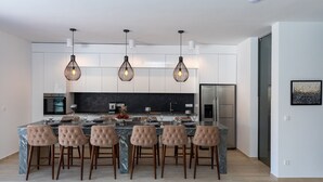 A modern kitchen with a central island, pendant lighting, and a stainless steel refrigerator. - Villa Delux View (Slivno)