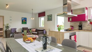 Eine moderne Küche mit weißen und rosafarbenen Schränken, einer Edelstahl-Dunstabzugshaube und einer Kaffeemaschine.