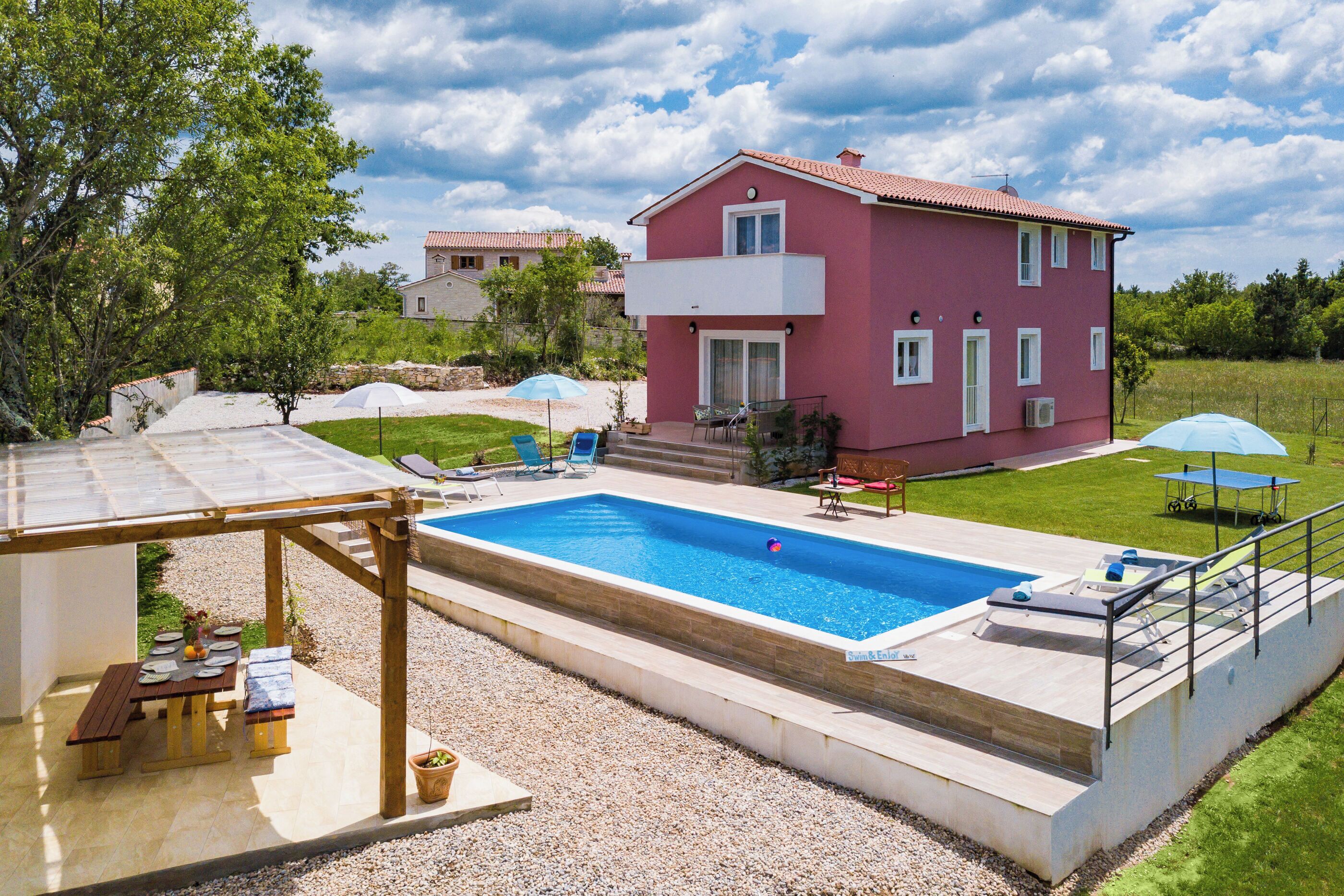 Una casa a due piani con piscina, area relax all'aperto e giardino.