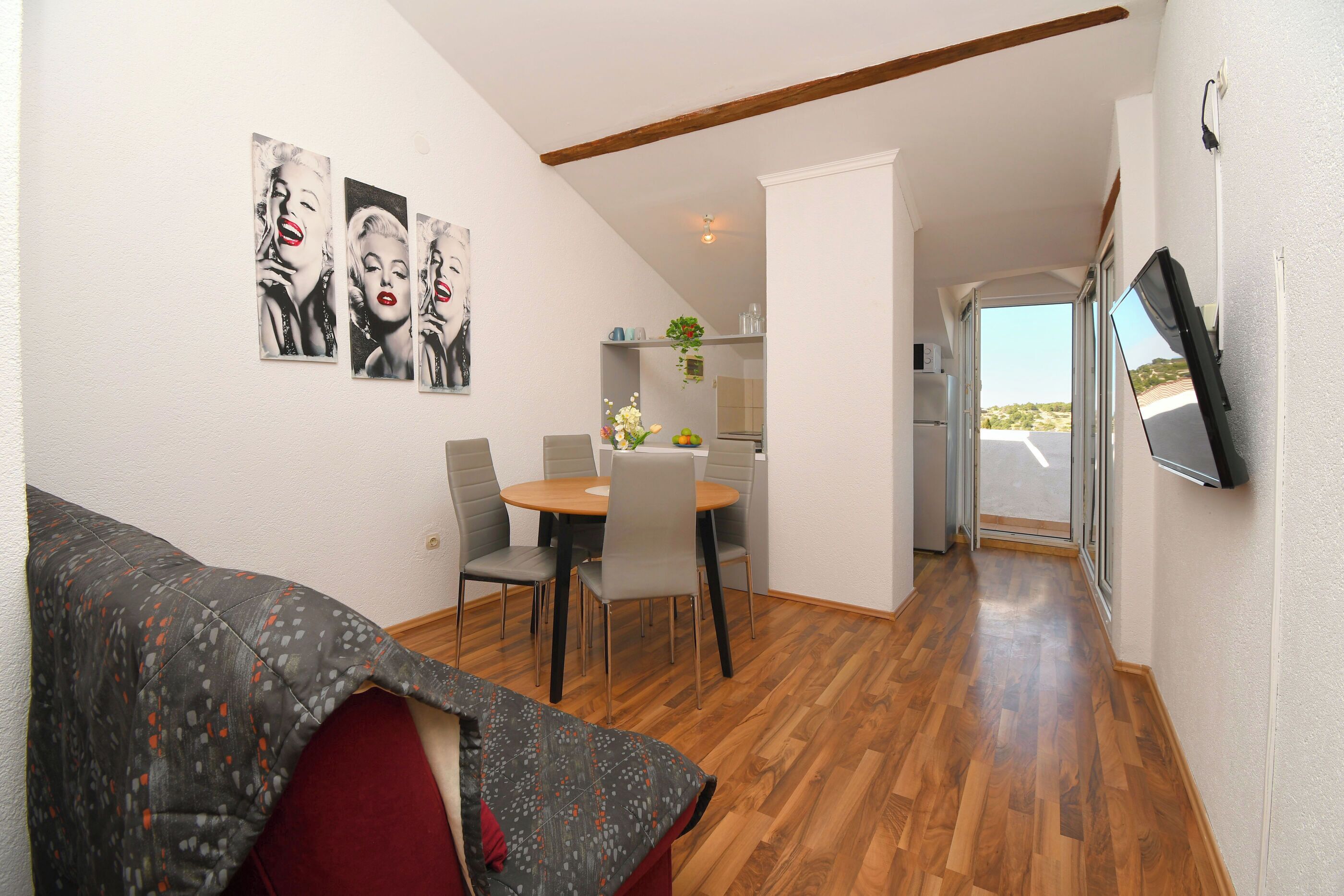 A compact living space with a dining area, a sofa, and artwork on the walls.