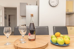 Un tavolo da pranzo con una bottiglia di vino, due bicchieri e un piatto di frutta.