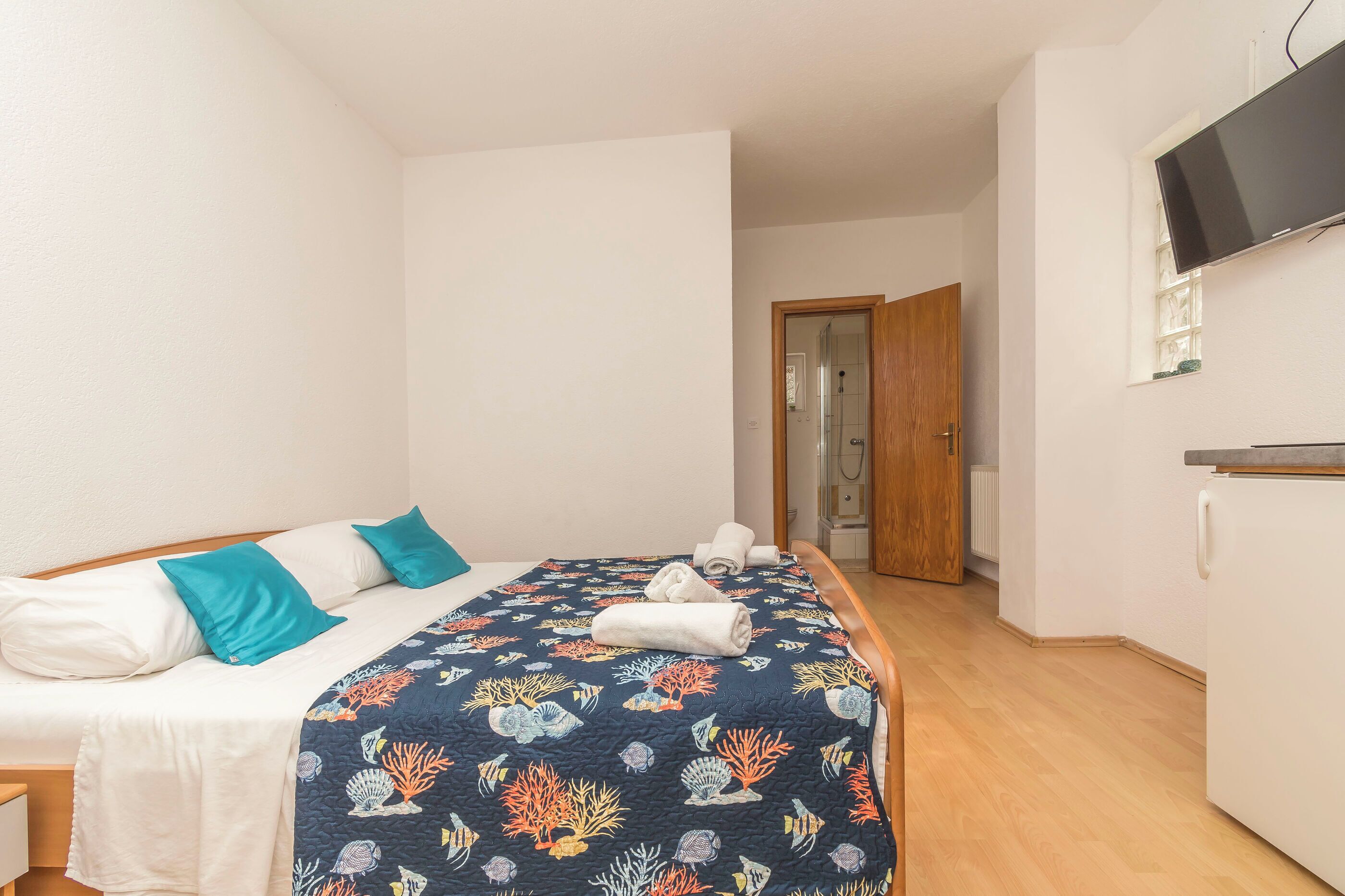 Un dormitorio con una cama, un televisor y una puerta que da a otra habitación.