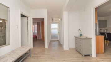 A narrow hallway with a bench, a dresser, and a door leading to a room with a shower.