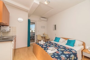 Una camera d'albergo compatta con un letto, un comodino e angolo cottura.