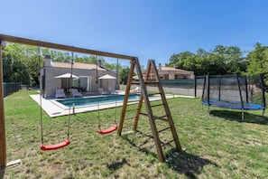 A backyard with a swing set, a trampoline, and a swimming pool. - Villa Tersaz (Sveta Nedelja)