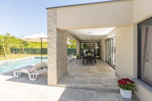 A covered patio area with a pool, outdoor seating, and a dining table. - Villa Tersaz (Sveta Nedelja)