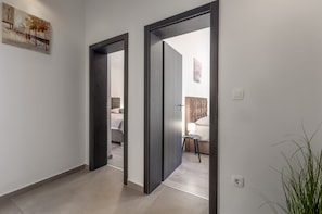 A hallway with two doors leading to bedrooms, a painting on the wall, and a potted plant. - Villa Tersaz (Sveta Nedelja)