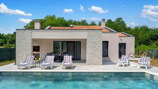 A modern house with a swimming pool, stone facade, and a patio with lounge chairs. - Villa Tersaz (Sveta Nedelja)