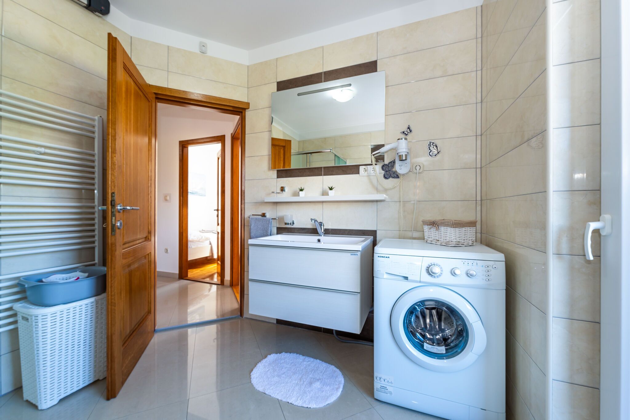 A modern bathroom with a washing machine, a sink, and a mirror.