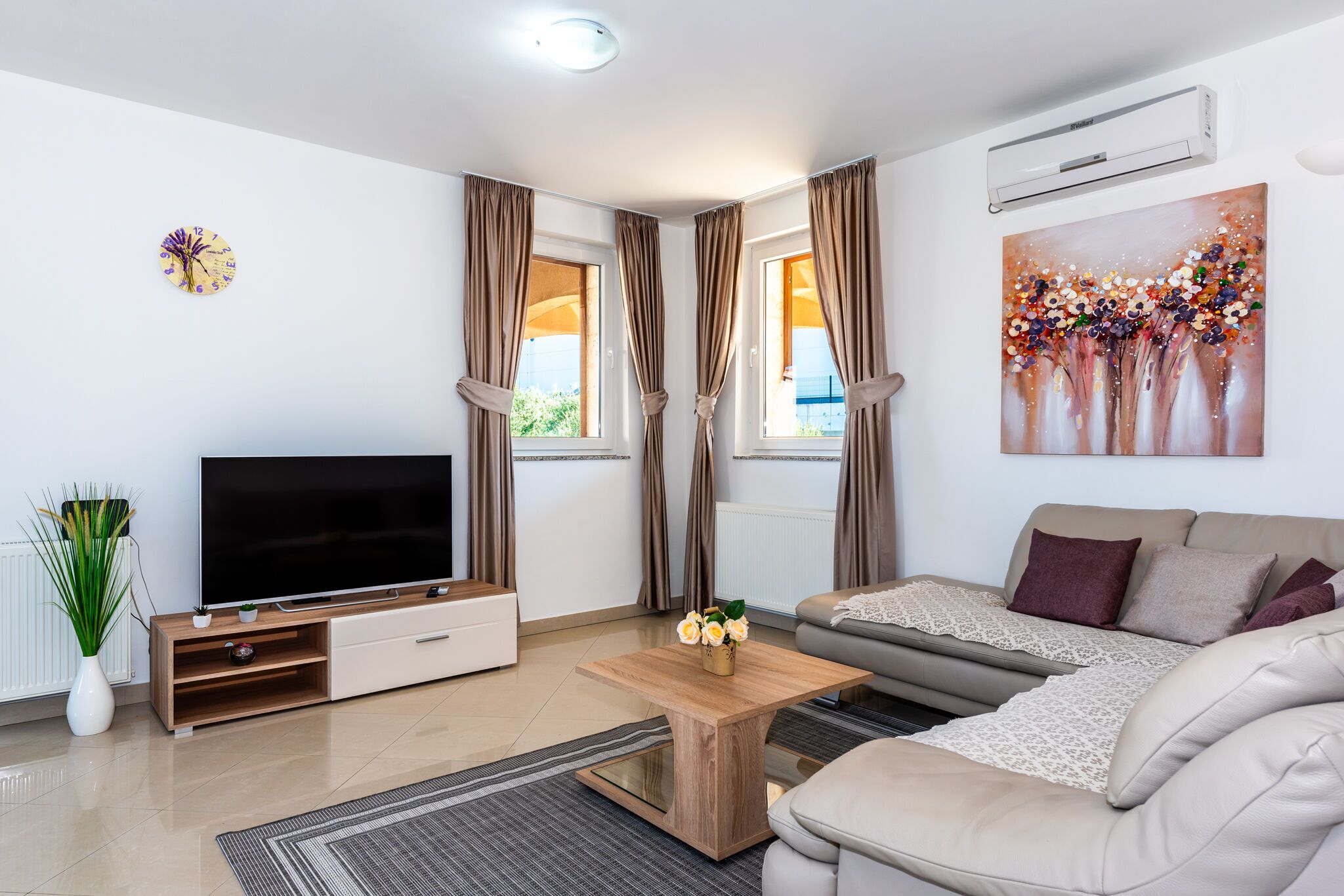 Un salon moderne avec un téléviseur à écran plat, une table basse en bois, un canapé et un tableau accroché au mur.