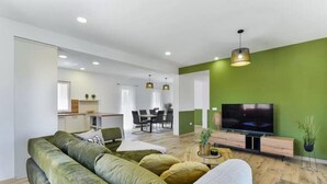 A modern living room with a green sofa, a TV, and a dining area in the background. - Villa St Vid 4 (Privlaka)