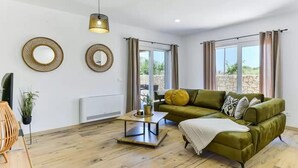 A modern living room with a green sofa, two round mirrors, a hanging light fixture, and a wooden coffee table. - Villa St Vid 4 (Privlaka)
