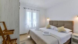 A hotel room with a bed, bedside tables, a wooden chair, and a window with curtains. - Villa St Vid 4 (Privlaka)