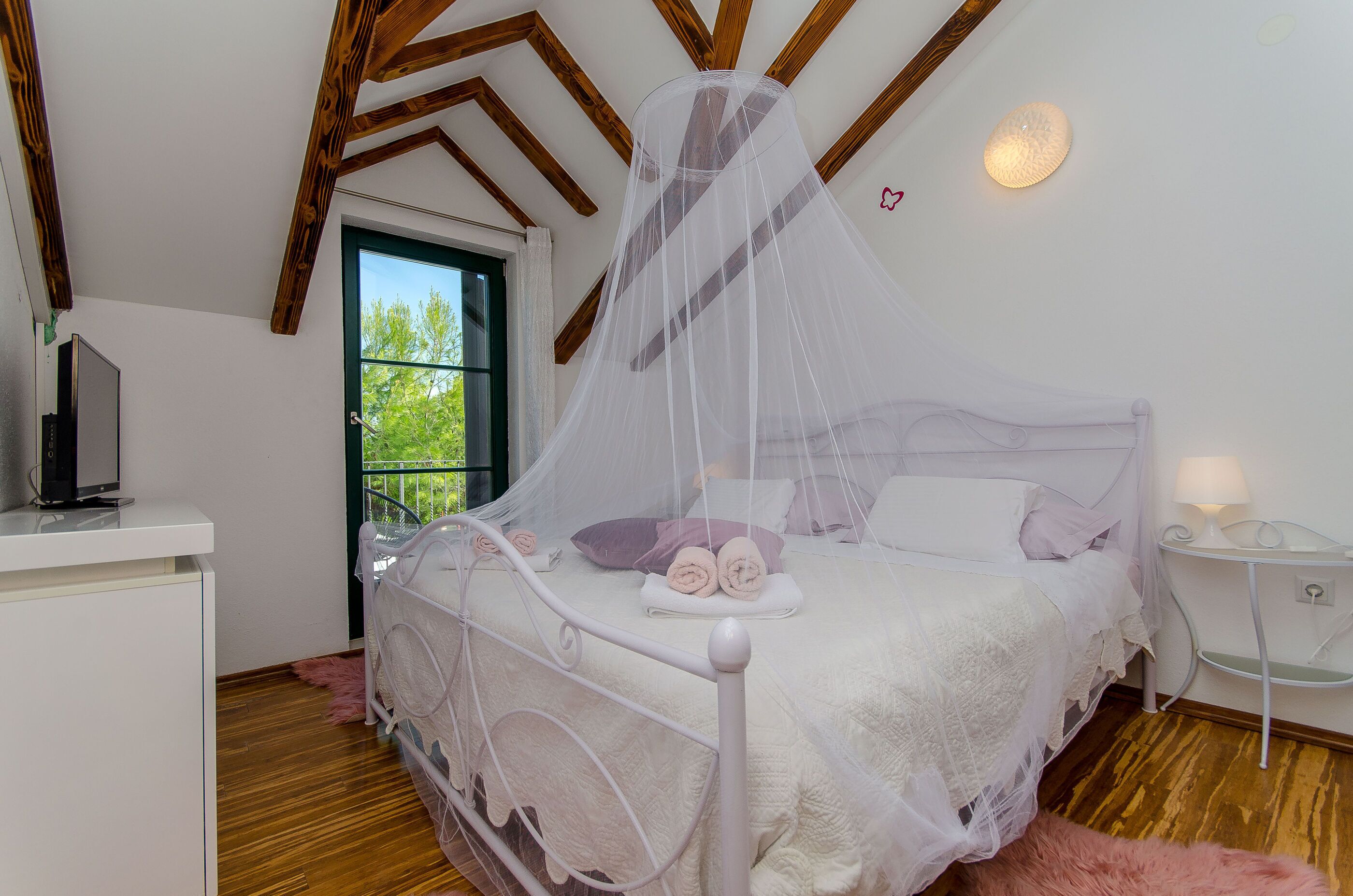 Camera da letto con un letto a baldacchino, un comodino con una lampada e vista sul verde circostante.