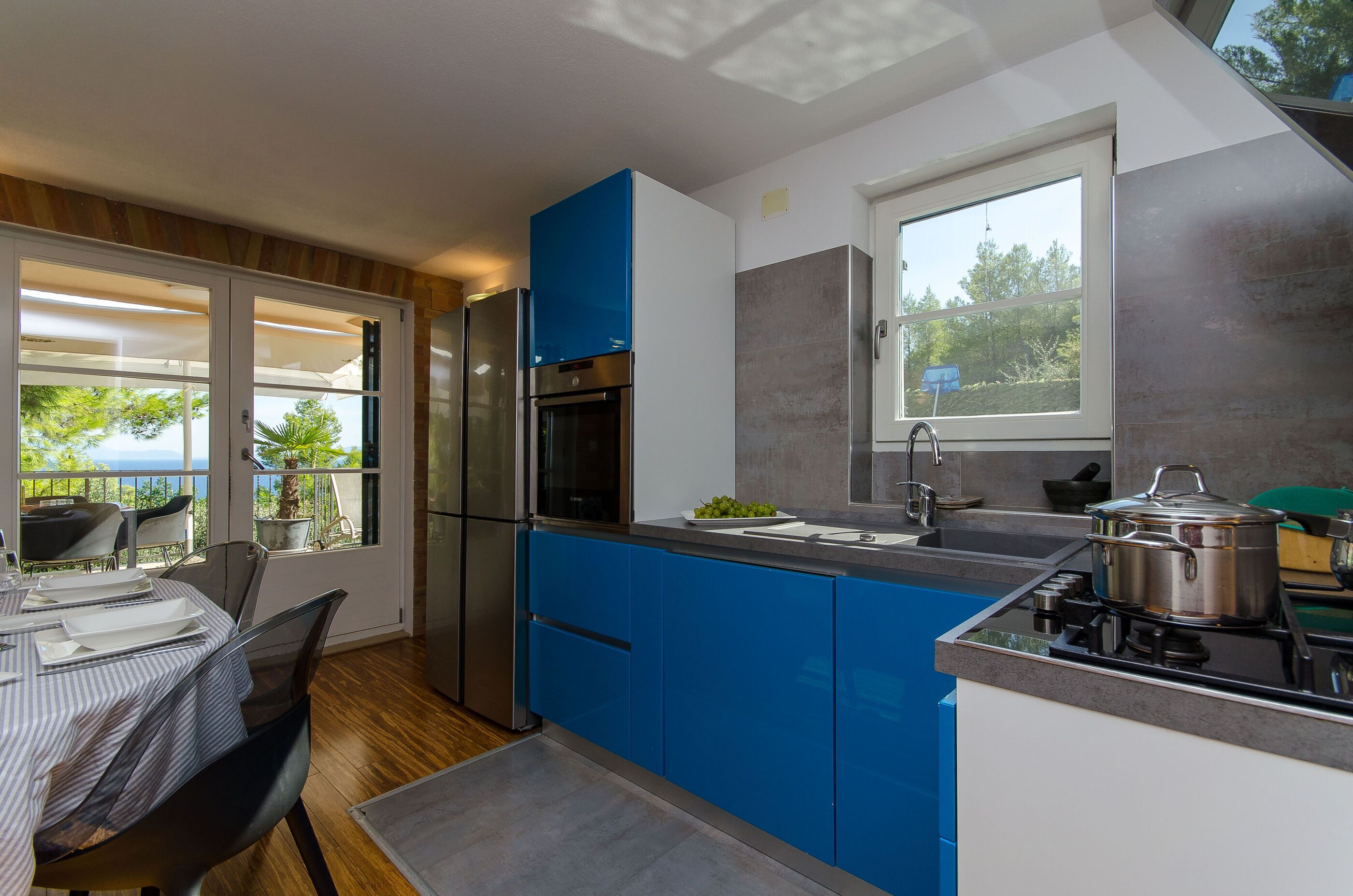 A modern kitchen with blue cabinets, a stainless steel refrigerator, and a gas stove.
