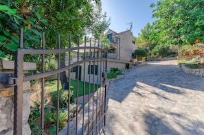 Una casa de piedra con entrada pavimentada y una puerta de metal.