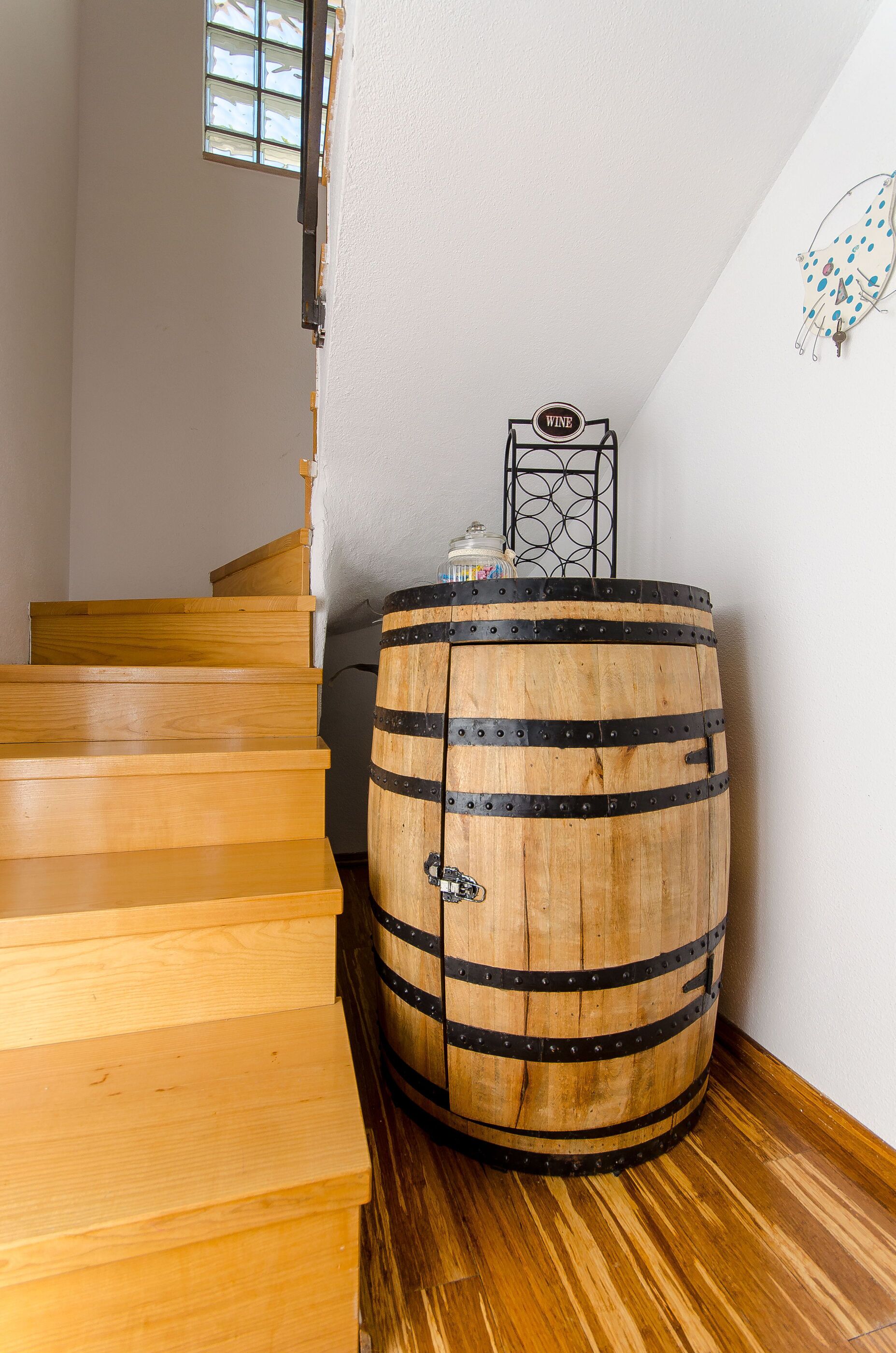 A wooden barrel with metal bands, a wooden staircase, and a small decorative item on the wall.