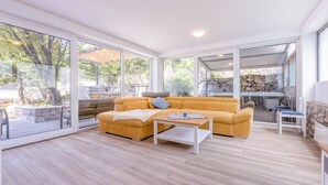A modern living room with a yellow sofa, a wooden coffee table, and large glass doors leading to an outdoor area. - Villa Turquoise Breeze (Novi Vinodolski)