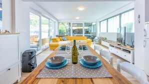 A modern living room with a wooden dining table set for two, a sofa, and a stone fireplace. - Villa Turquoise Breeze (Novi Vinodolski)