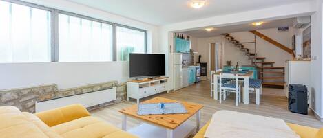 A living room with a sofa, a TV, and a dining area with a table and chairs.