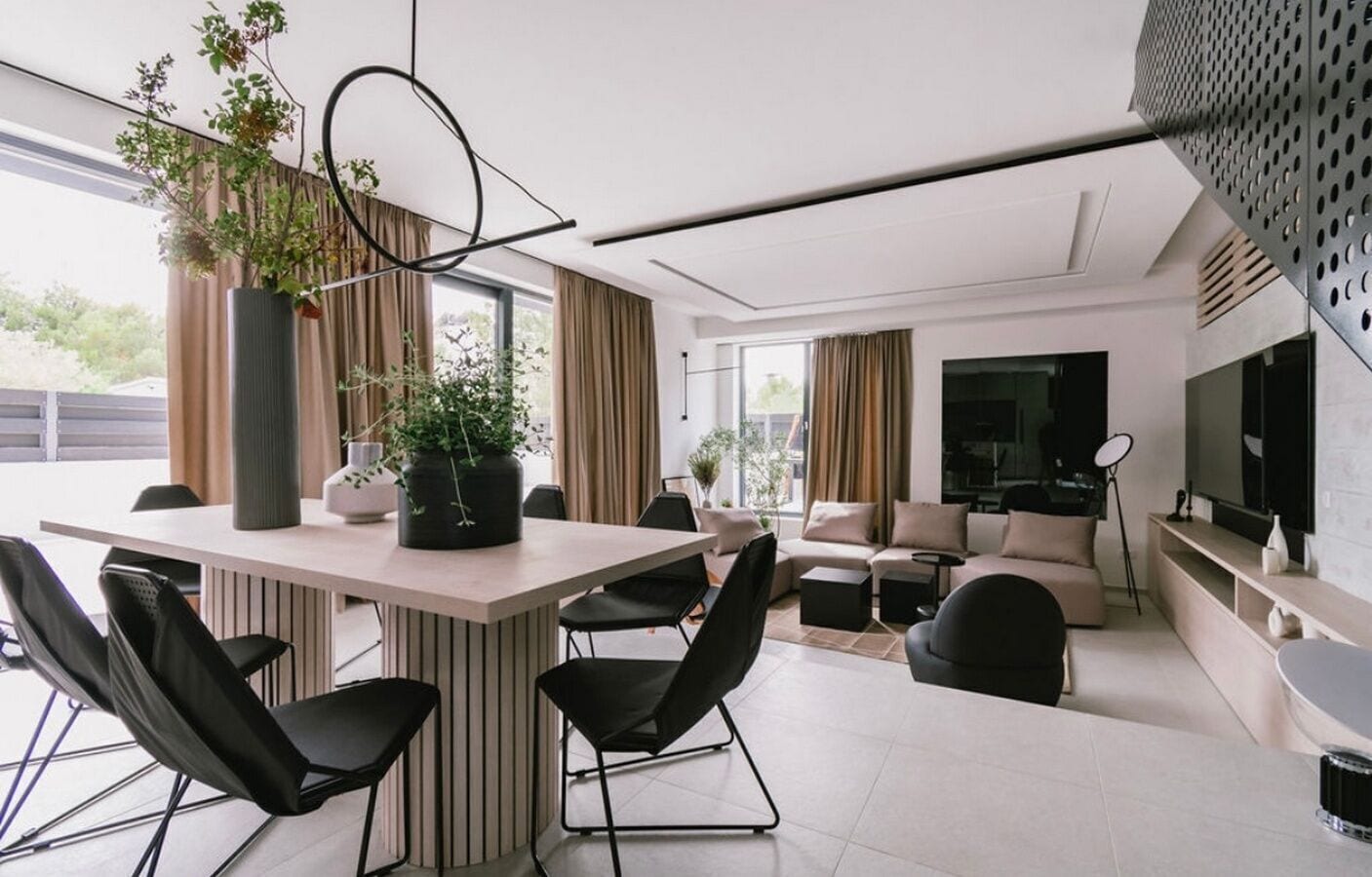 A modern living room with a dining area, large windows, and a flat-screen TV.