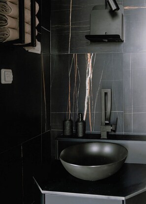 A modern bathroom with a black sink, a towel rack, and a soap dispenser. - Villa Chic (Vodice)