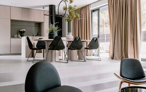 Un espace repas moderne avec une longue table, quatre chaises noires et une plante placée au centre.