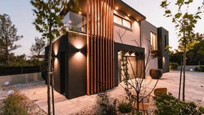 A modern two-story house with a dark facade, wooden slats, and a well-lit exterior. - Villa Chic (Vodice)