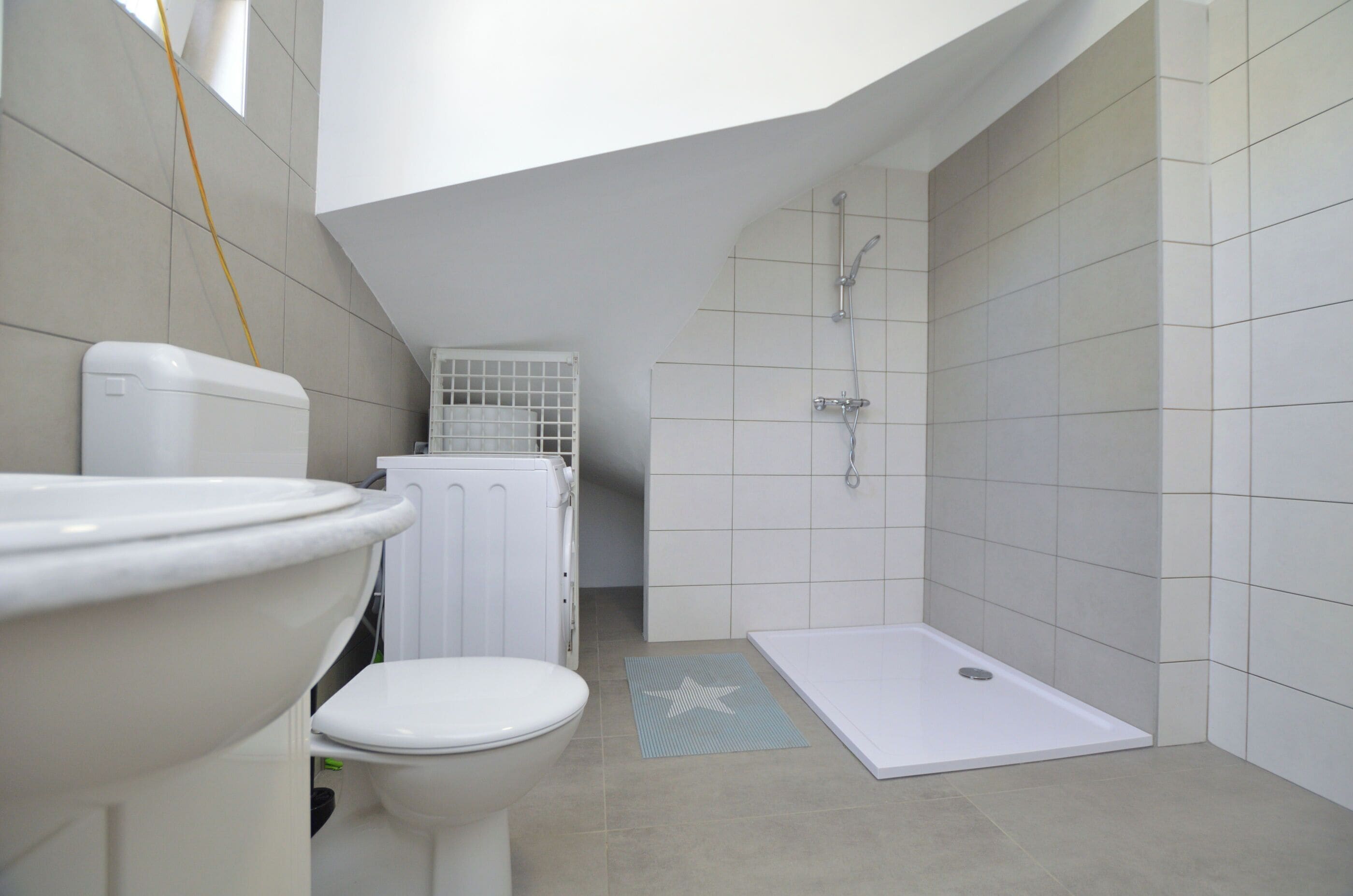A modern bathroom with a toilet, shower, and a small window.