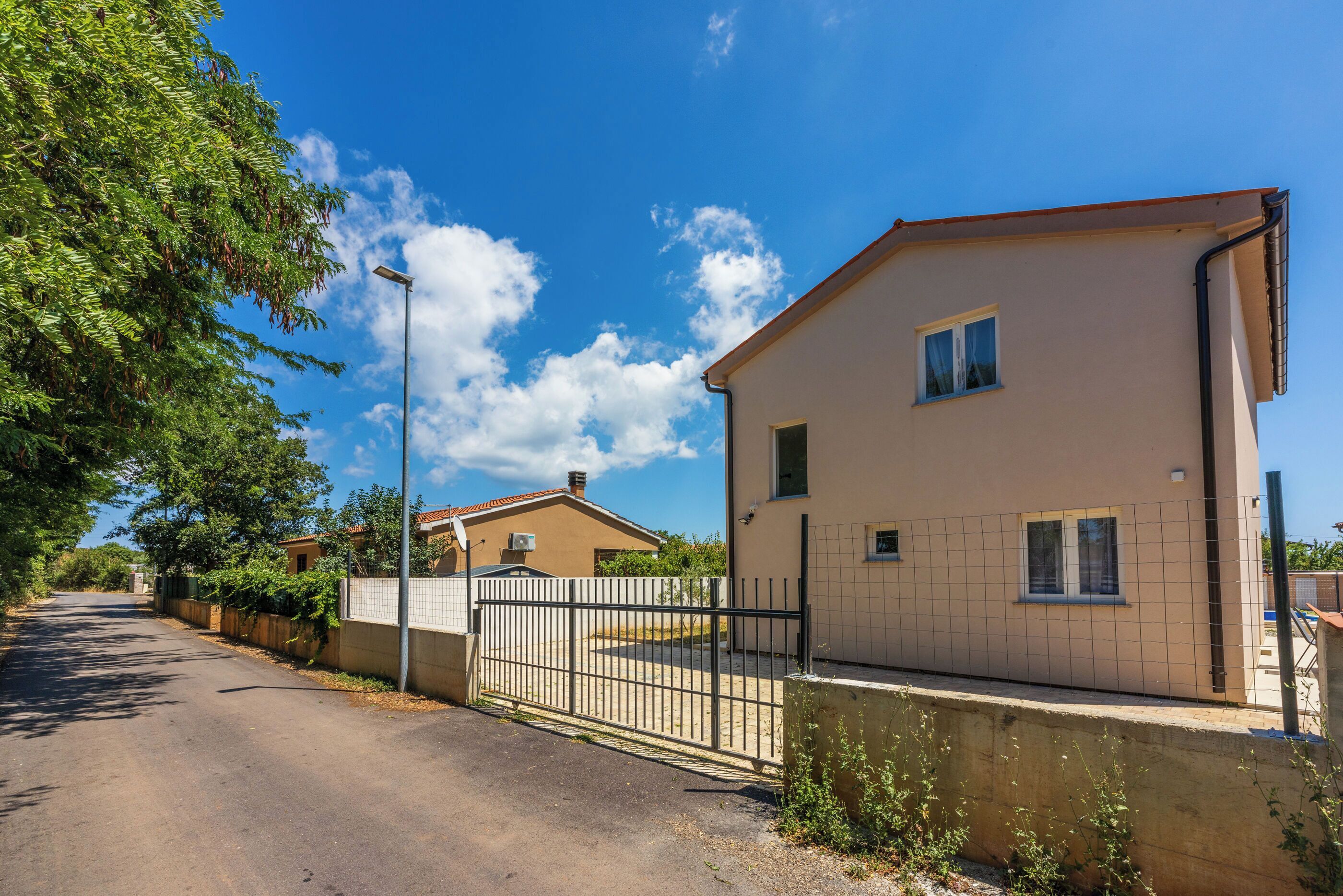 Een woonstraat met huizen, een hekpoort en een helderblauwe lucht.