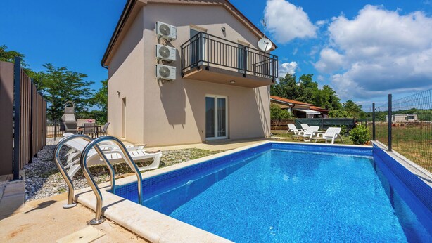 A swimming pool with lounge chairs, a balcony with air conditioning units, and a clear blue sky. - Villa Maluma (Medulin)
