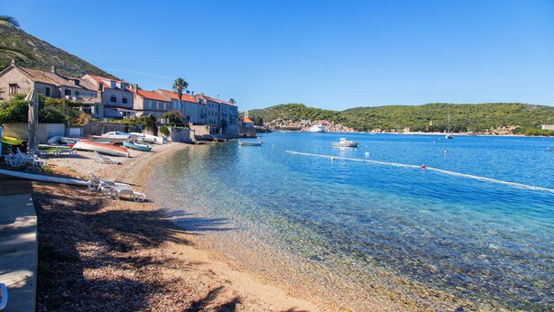 A coastal town with clear waters, boats, and buildings along the shore.
