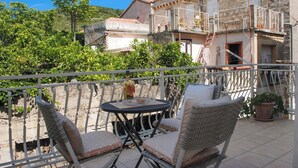 A balcony with wicker furniture, a small table, and potted plants.