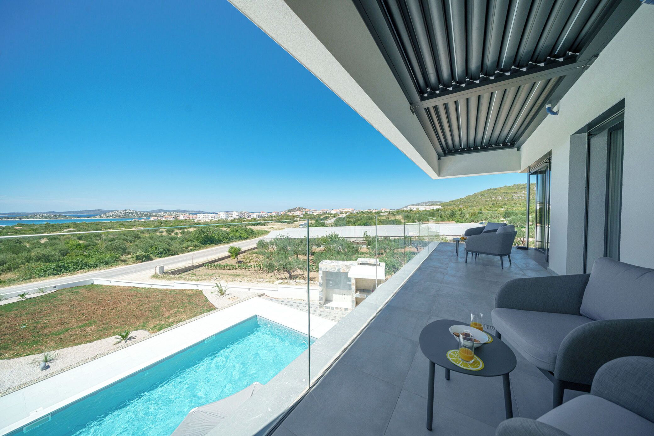 Ein moderner Balkon mit Pool, Sitzgelegenheit im Freien und Blick auf die Landschaft.