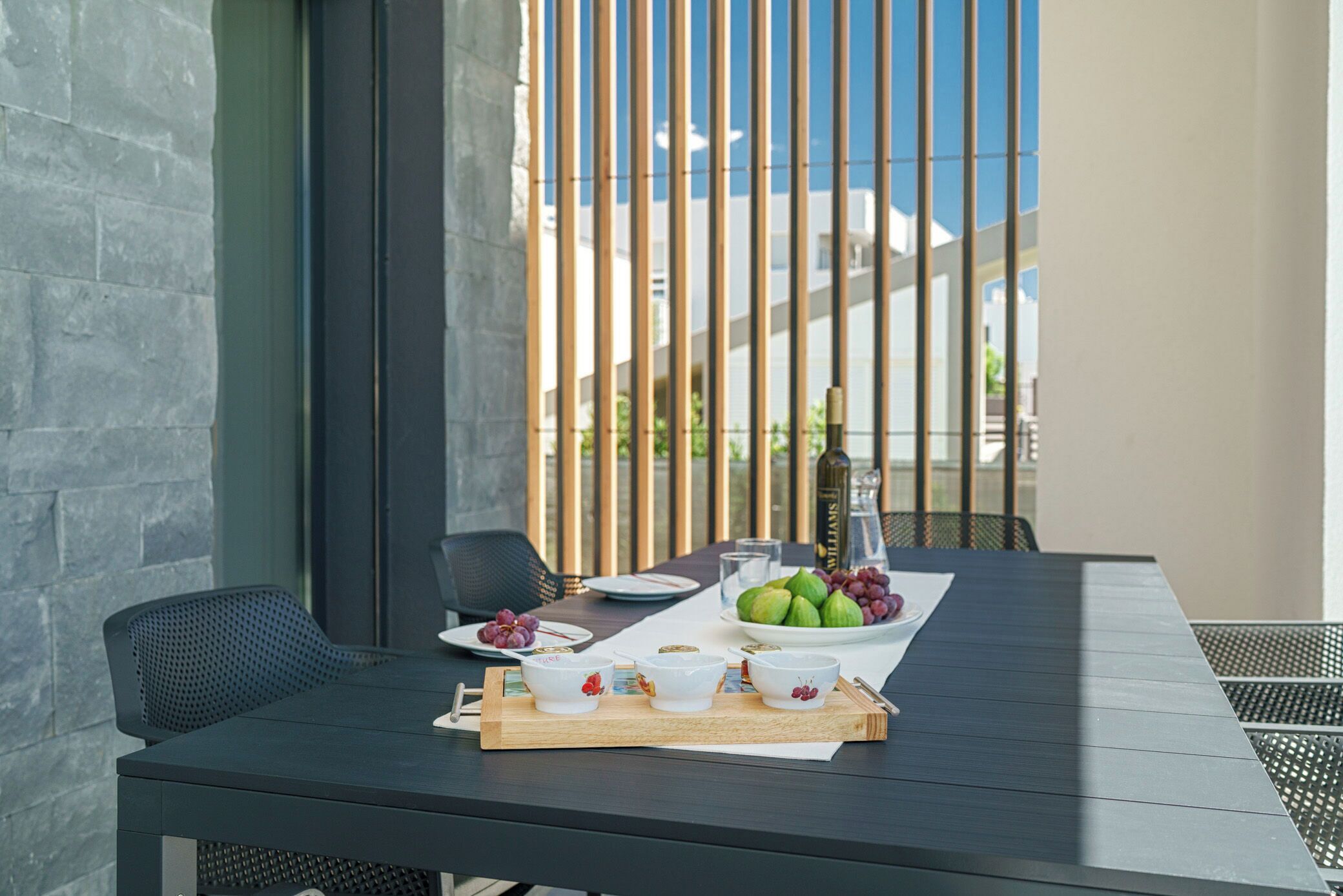 A dining table with a tray of bowls, a plate of fruits, and a bottle of water.