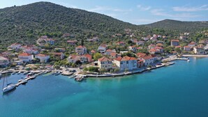 A coastal town with buildings along the waterfront, a marina with boats, and hills in the background. - Apartments Tiho II (Marina)