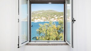 A window with a view of a coastal town and a body of water. - Apartments Tiho II (Marina)