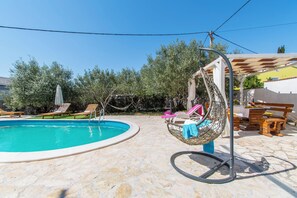 Ein Pool mit Liegestühlen und einer Hängematte.