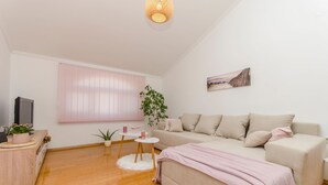 Un salon moderne avec un canapé, un téléviseur, une plante et un tableau au mur.