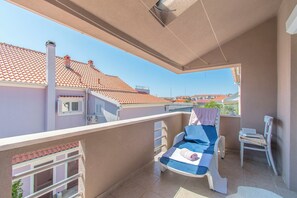 Un balcone con una sdraio, una sedia e un tavolino.