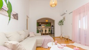 Un salon moderne avec un canapé, une table à manger décorée de bougies et une cuisine en arrière-plan.